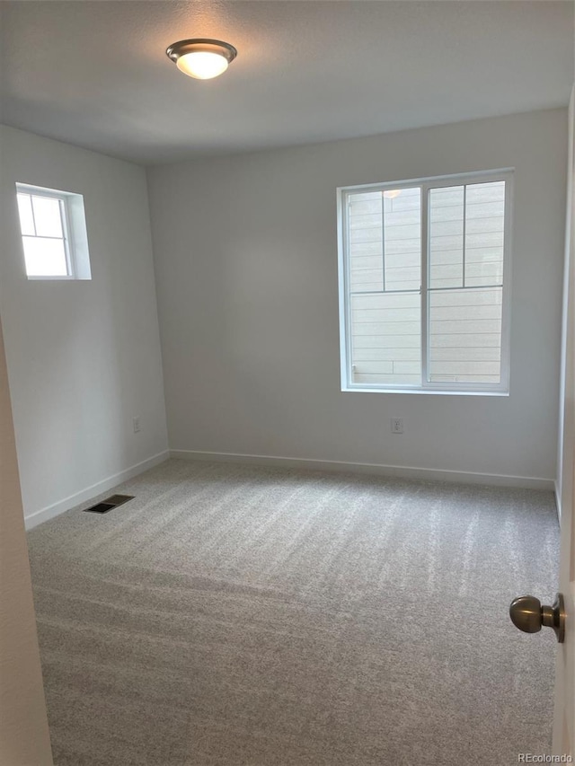 carpeted empty room with visible vents and baseboards