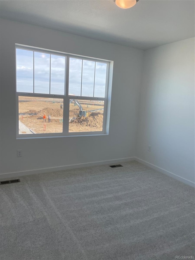 carpeted spare room with visible vents and baseboards