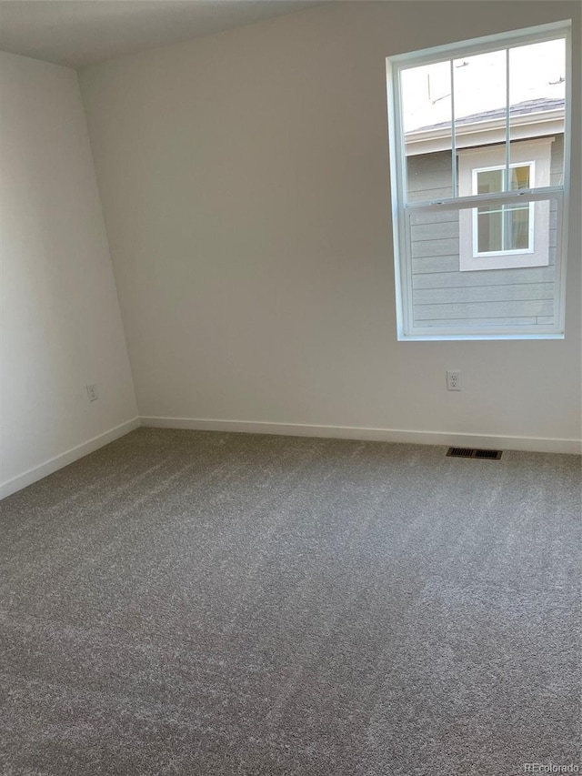 carpeted spare room with visible vents and baseboards