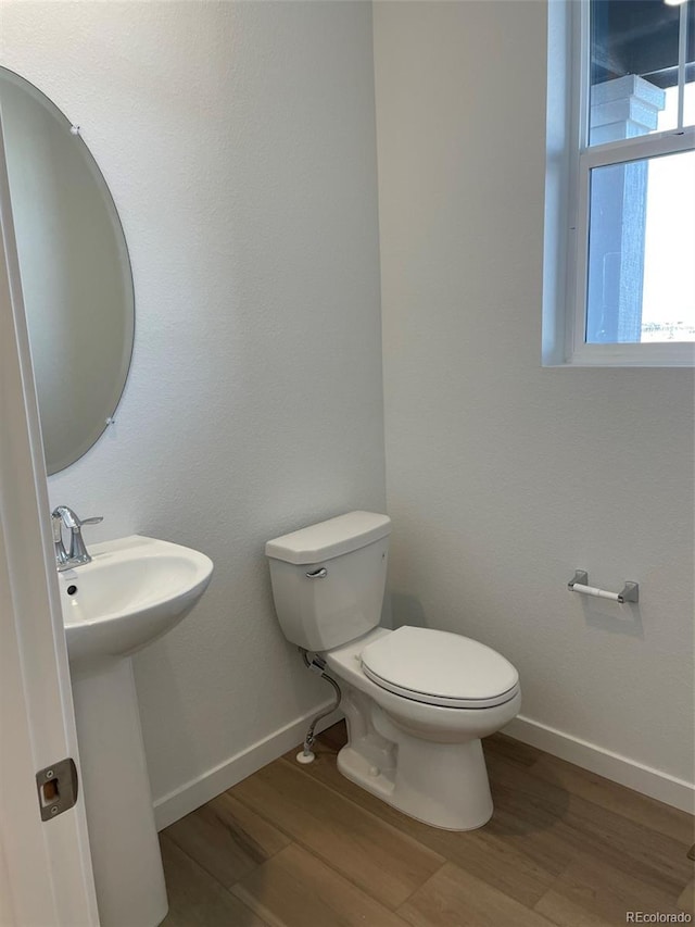 bathroom featuring toilet, wood finished floors, baseboards, and a sink