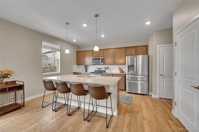 7465 E 157th Pl, Thornton, CO 80602 - kitchen with stainless steel appliances, a sink, light wood-type flooring, an island with sink, and recessed lighting