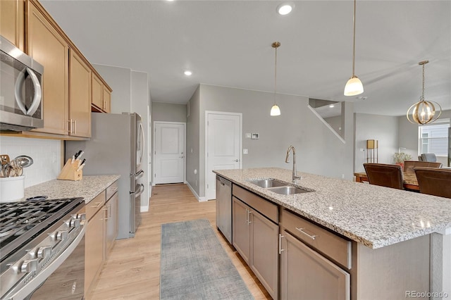 7465 E 157th Pl, Thornton, CO 80602 - kitchen featuring a sink, stainless steel appliances, light wood-style floors, tasteful backsplash, and a center island with sink