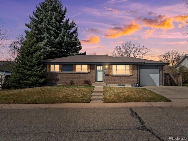 single story home featuring fence, a garage, a lawn, brick siding, and driveway