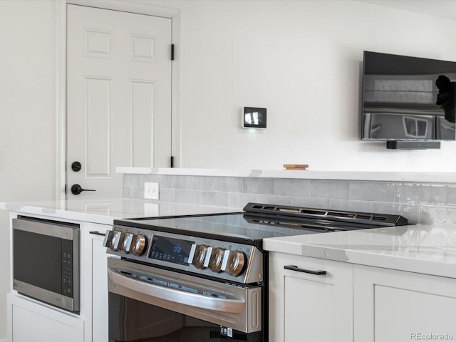 kitchen with white cabinetry, stainless steel appliances, light countertops, and tasteful backsplash