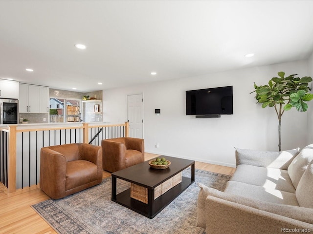 living room with baseboards, recessed lighting, and light wood-style floors