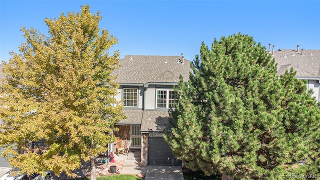 view of front of home with a garage, stone siding, driveway, roof with shingles, and stucco siding