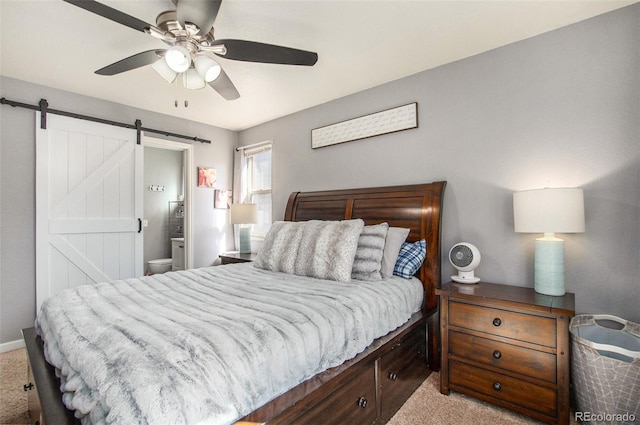 bedroom featuring ensuite bathroom, a barn door, ceiling fan, and light colored carpet