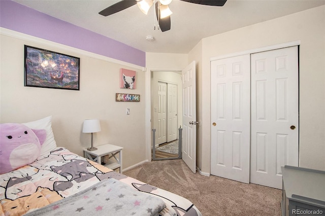 bedroom featuring a ceiling fan, a closet, light colored carpet, and baseboards