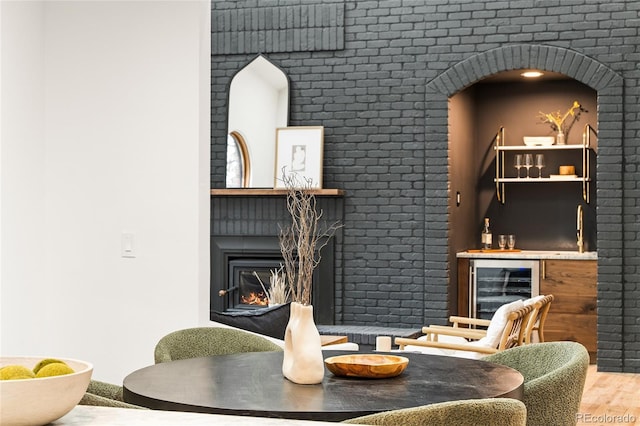 living room featuring brick wall, indoor wet bar, wood-type flooring, and beverage cooler