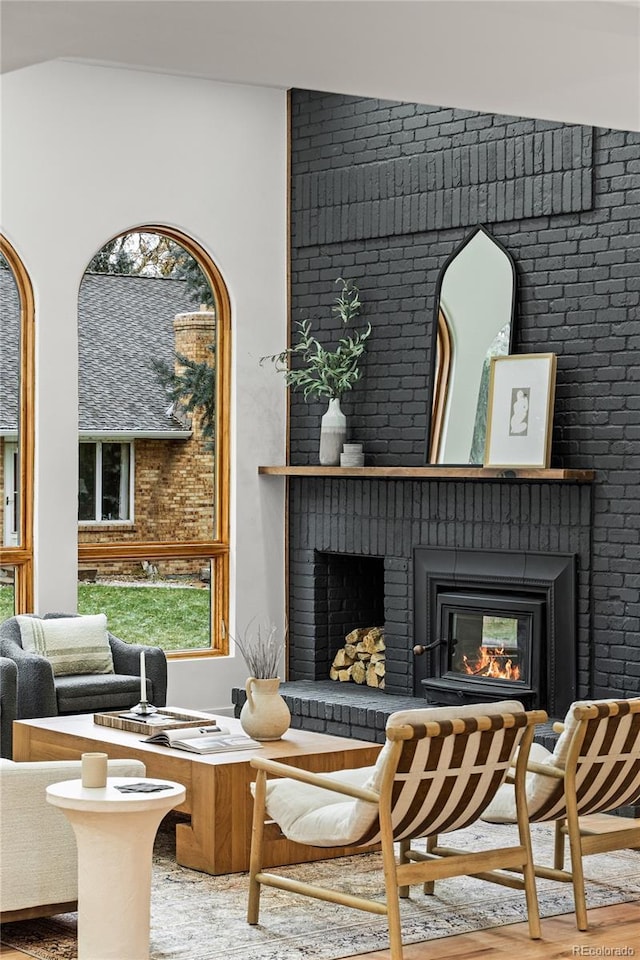 sitting room featuring hardwood / wood-style floors, brick wall, and vaulted ceiling