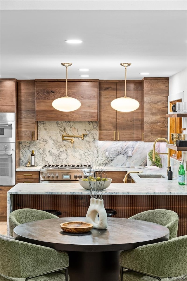 kitchen featuring decorative backsplash, sink, stainless steel appliances, and decorative light fixtures