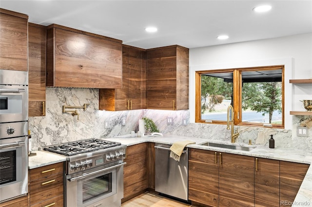 kitchen with decorative backsplash, light stone countertops, stainless steel appliances, sink, and light hardwood / wood-style floors