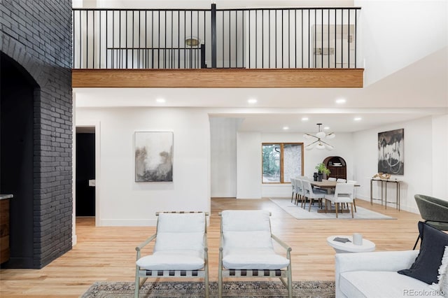 living room featuring light hardwood / wood-style floors, a high ceiling, and an inviting chandelier