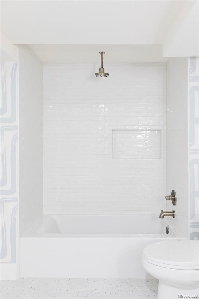 bathroom featuring toilet and tiled shower / bath