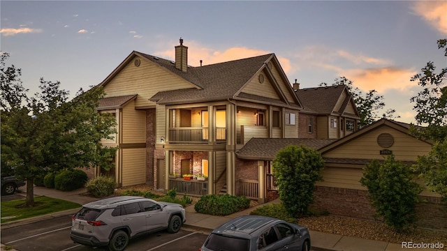 23456 E 5th Pl Unit 104, Aurora, CO 80018 - view of property with brick siding, uncovered parking, covered porch, a balcony, and a chimney