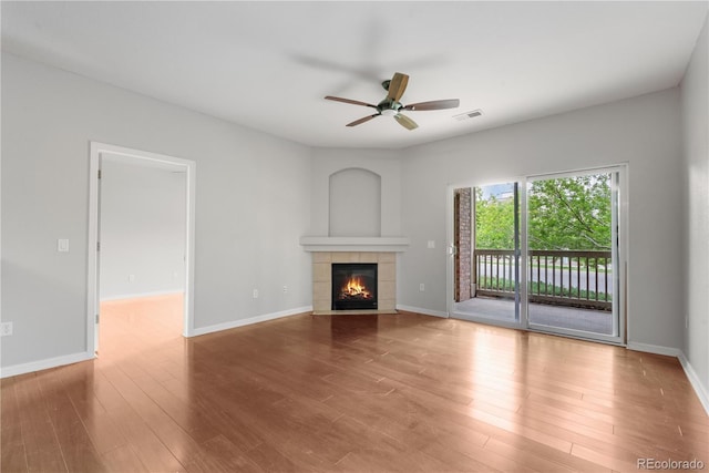 23456 E 5th Pl Unit 104, Aurora, CO 80018 - unfurnished living room featuring a tile fireplace, ceiling fan, and wood finished floors