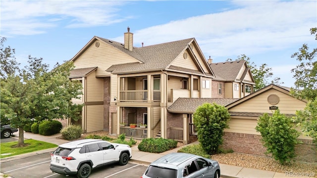 23456 E 5th Pl Unit 104, Aurora, CO 80018 - townhome / multi-family property featuring uncovered parking, brick siding, a chimney, a balcony, and roof with shingles