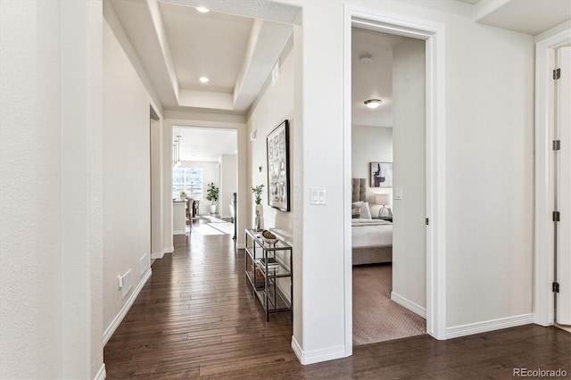 hallway featuring a tray ceiling and dark hardwood / wood-style floors