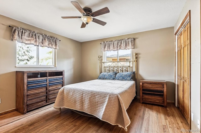 bedroom featuring multiple windows, light wood-type flooring, ceiling fan, and a closet