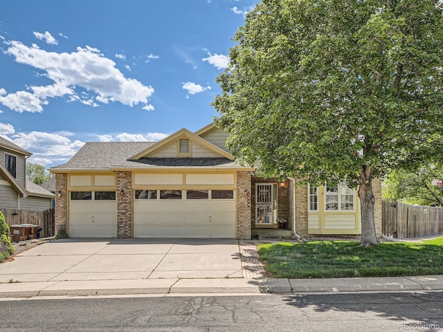 view of front facade featuring brick siding, fence, an attached garage, and concrete driveway