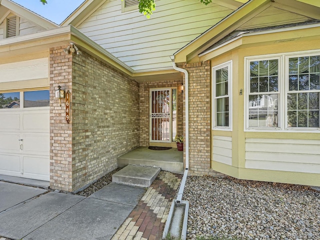 entrance to property with brick siding and a garage