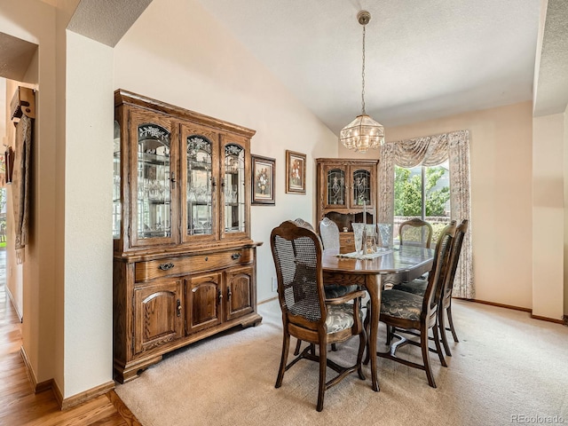 dining room with a chandelier, lofted ceiling, baseboards, and light carpet