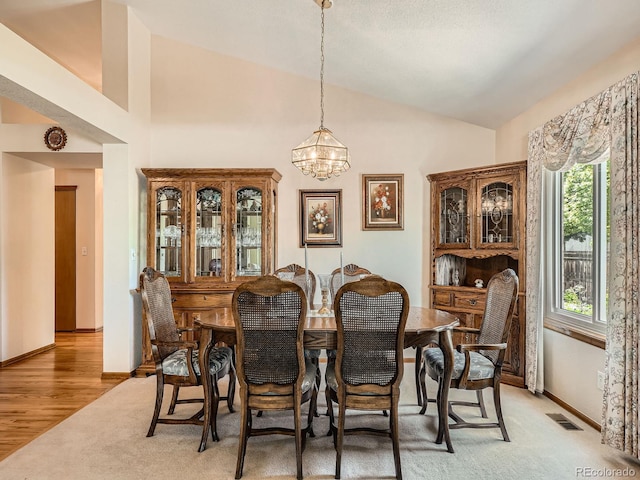 dining space with lofted ceiling, a chandelier, baseboards, and light wood finished floors