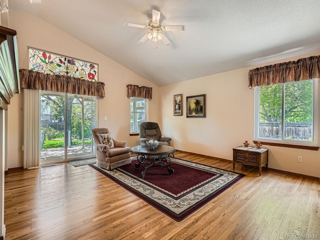 sitting room with wood finished floors, a ceiling fan, baseboards, and high vaulted ceiling