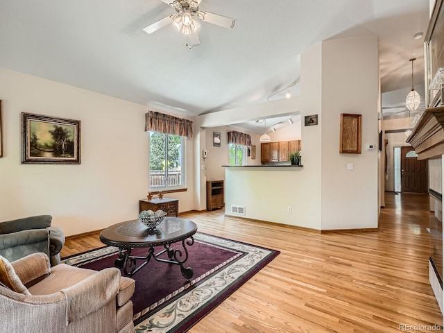 living room featuring lofted ceiling, a ceiling fan, light wood-style floors, baseboards, and rail lighting