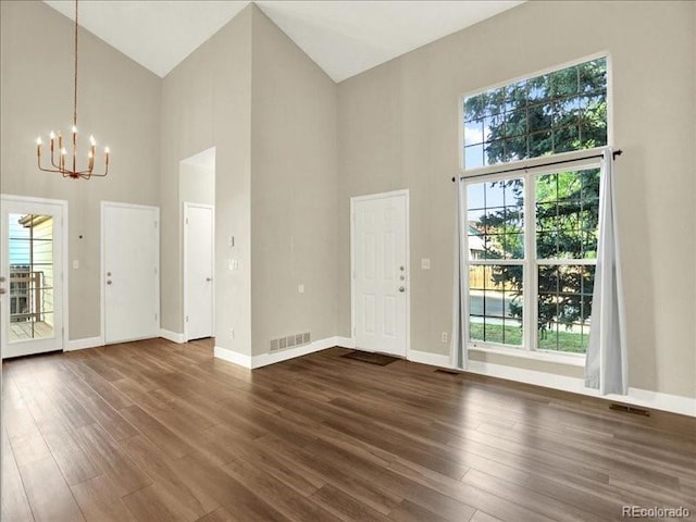 entryway with high vaulted ceiling, a chandelier, dark wood finished floors, and baseboards