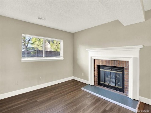 unfurnished living room with dark wood-type flooring, a fireplace, a textured ceiling, and baseboards