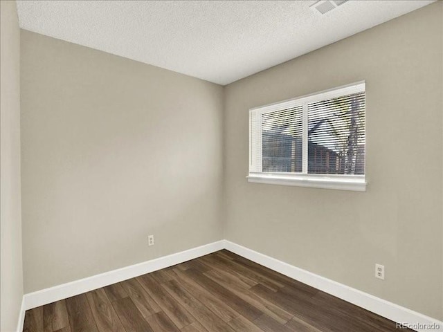 empty room with dark wood-style flooring, baseboards, and a textured ceiling