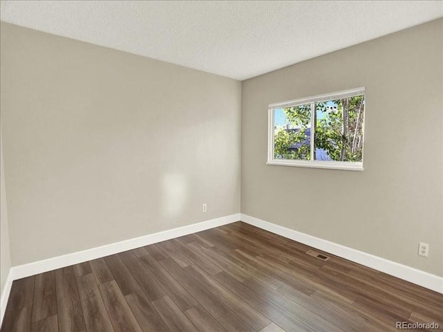spare room with baseboards, dark wood-style flooring, and a textured ceiling