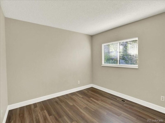unfurnished room with dark wood finished floors, baseboards, and a textured ceiling