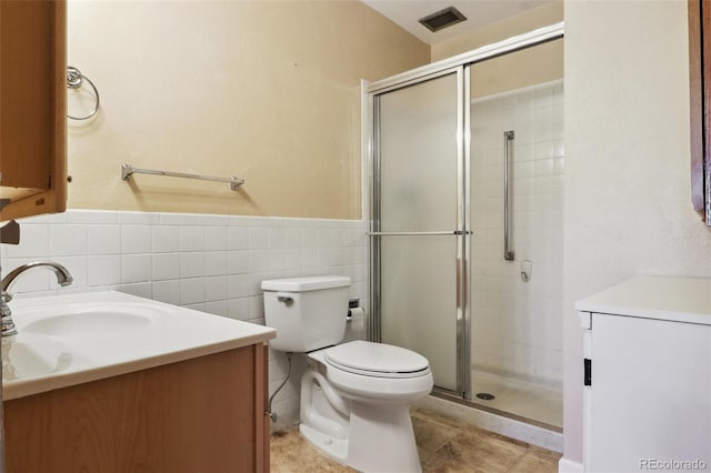 bathroom featuring tile patterned flooring, vanity, toilet, and tile walls