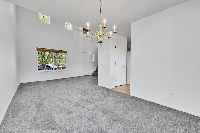 empty room with baseboards, carpet flooring, stairs, and a notable chandelier