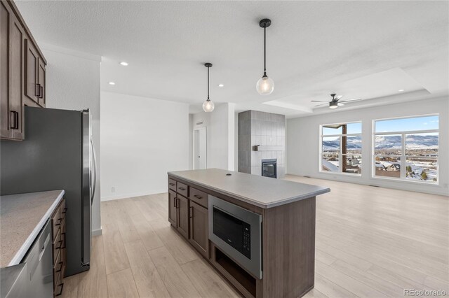 kitchen with hanging light fixtures, stainless steel appliances, dark brown cabinets, and a center island