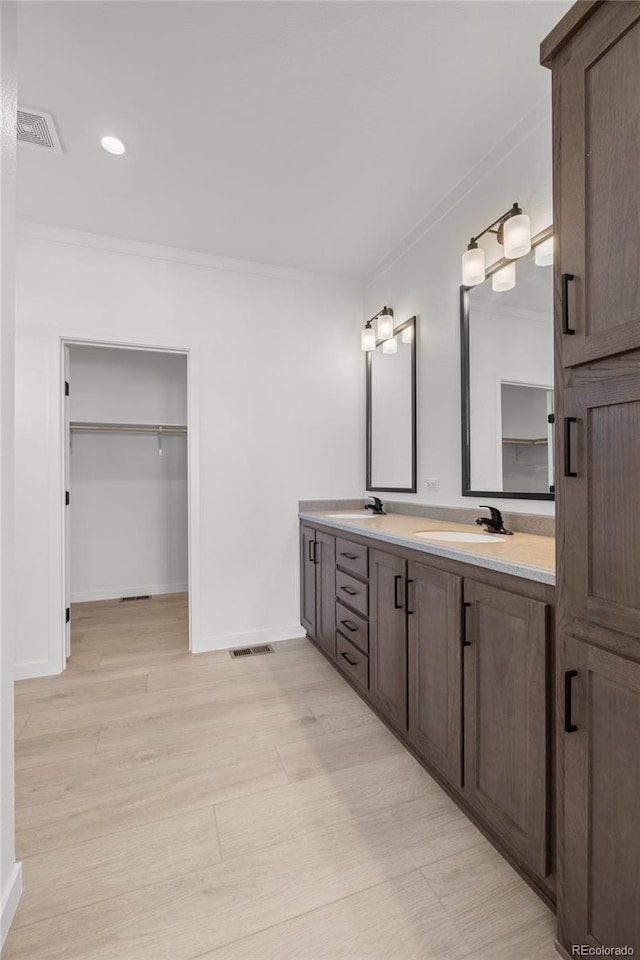 full bath with ornamental molding, visible vents, a sink, and double vanity