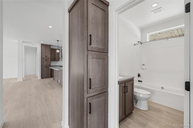 full bathroom with visible vents, shower / bathing tub combination, toilet, vanity, and wood finished floors