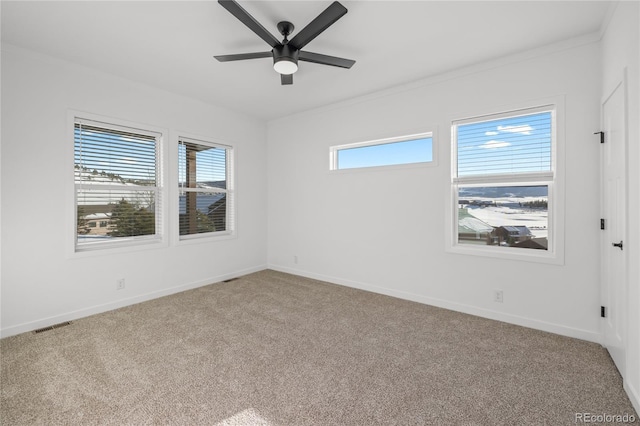 spare room with a healthy amount of sunlight, light carpet, visible vents, and baseboards