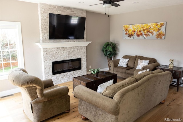 living room with light hardwood / wood-style floors, a fireplace, and ceiling fan