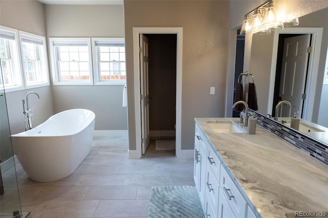 bathroom with a notable chandelier, a tub to relax in, vanity, and tile patterned floors