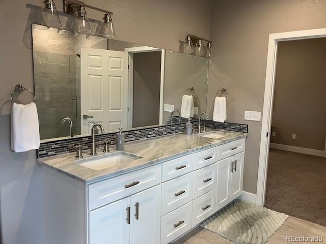 bathroom featuring a shower with door, vanity, and tasteful backsplash