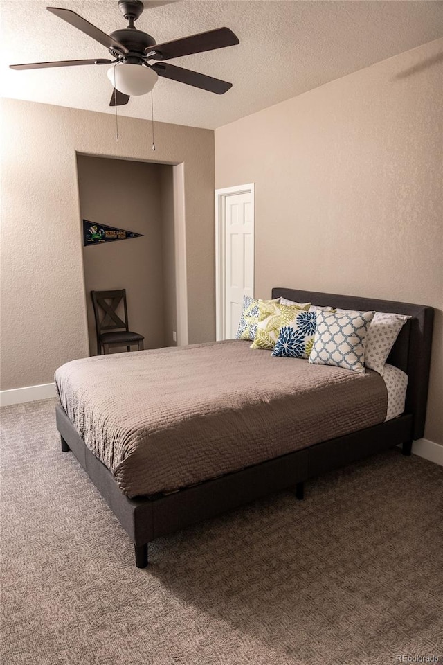 bedroom with ceiling fan, carpet floors, and a textured ceiling