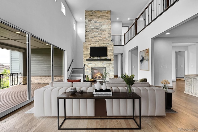 8179 S Kellerman Cir, Aurora, CO 80016 - living room featuring a high ceiling, a stone fireplace, wood finished floors, recessed lighting, and stairway