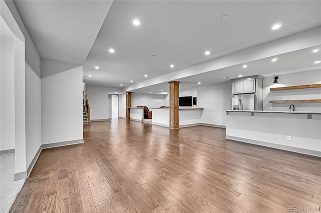 8179 S Kellerman Cir, Aurora, CO 80016 - unfurnished living room featuring wood finished floors, a sink, recessed lighting, baseboards, and ornate columns