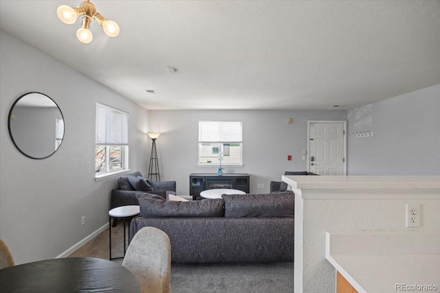 carpeted living room with baseboards, a notable chandelier, and visible vents