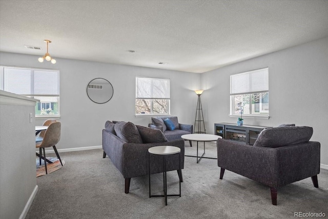 carpeted living area with baseboards, visible vents, and a textured ceiling