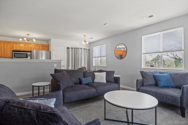 carpeted living room featuring baseboards, a notable chandelier, and visible vents