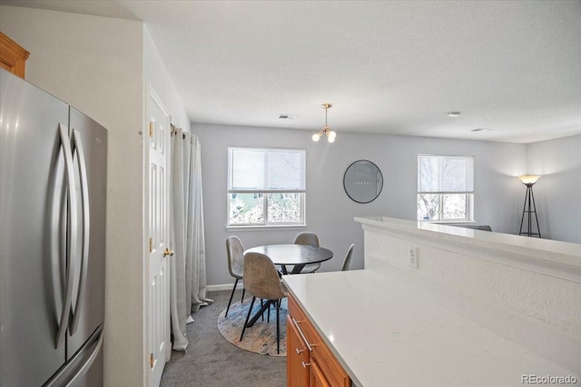 kitchen featuring freestanding refrigerator, a wealth of natural light, brown cabinets, and light colored carpet